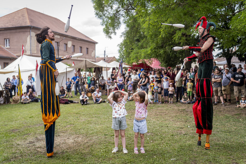 Gólyalábas mutatványozás, kikiáltás és gyerekműsor